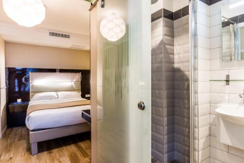 a bathroom with a bed and a shower and a sink at District Republique in Paris