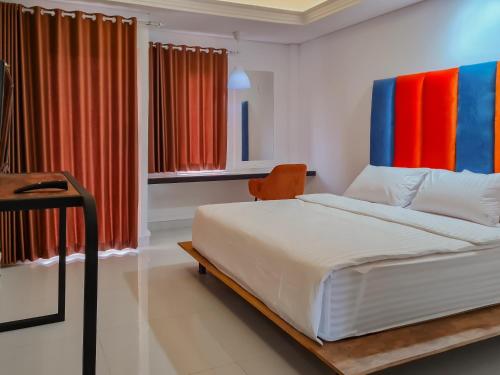 1 dormitorio con cama blanca y cortinas coloridas en Sans Hotel Grand Sabaraya Cikampek, en Karawang