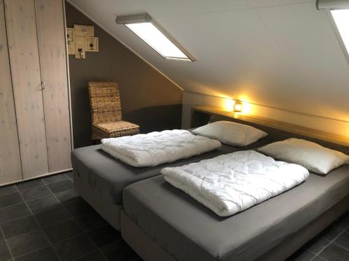 - une chambre avec deux lits et une chaise dans l'établissement De Graanzolder, à Hoofdplaat