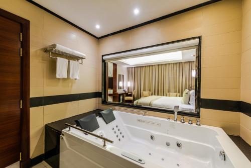 a bathroom with a tub and a large mirror at Blue Diamond Hotel Jeddah in Jeddah