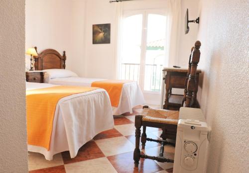 een kamer met 2 bedden, een bureau en een raam bij Hostal Puerto Lepe in Lepe
