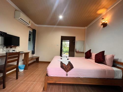 a bedroom with a large bed and a desk at Ingtarn Ressort At thasala in Ban Nai Thung