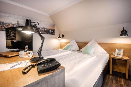 a room with a bed and a desk with a lamp at City Hotel in Geilenkirchen