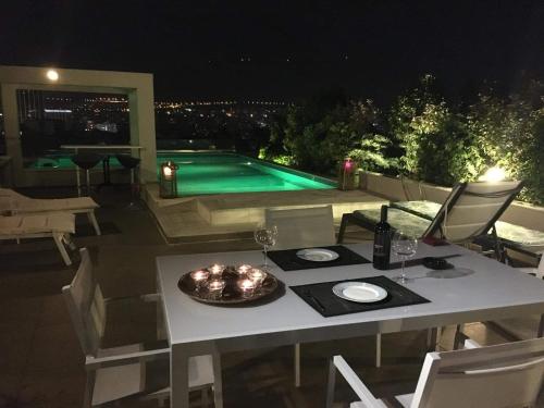 a table and chairs with a pool in the background at Athens Lycabettus Hill Penthouse, Private Roof Garden & Pool in Athens