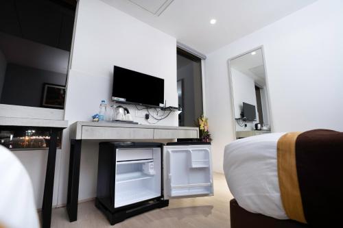 a white bedroom with a bed and a tv at Poiisse in Kolkata
