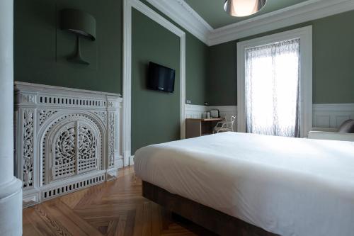 a bedroom with a white bed and a fireplace at Petit Palace Lealtad Plaza in Madrid
