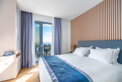 um quarto com uma cama e uma grande janela em Glyfada Riviera Hotel em Atenas