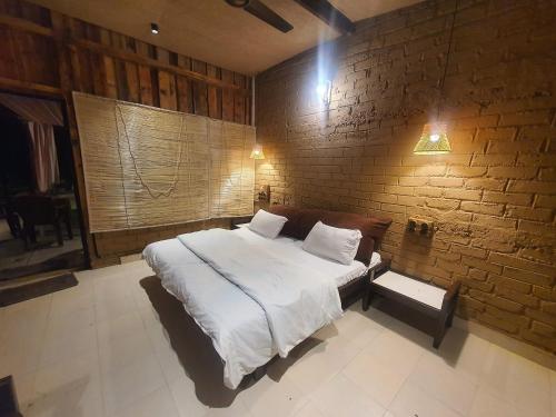 a bedroom with a large bed and a brick wall at Varenya Agro Resort in Kolvan