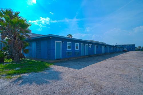 un edificio blu con una palma accanto di Monterrey Motel Padre Island, Corpus Christi BY OYO a Corpus Christi