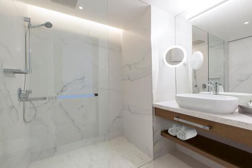 a white bathroom with a sink and a shower at Makedonia Palace in Thessaloniki