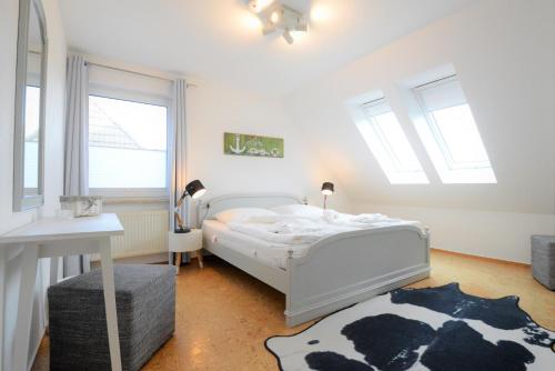 ein Schlafzimmer mit einem weißen Bett und einem Kuhteppich in der Unterkunft Ferienhaus Rügen in Pantow
