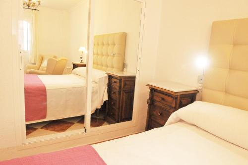 a bedroom with two beds and a mirror at Hostal Puerto Lepe in Lepe