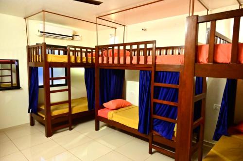 ein Zimmer mit drei Etagenbetten mit blauen Vorhängen in der Unterkunft Bay Stays near white town in Puducherry