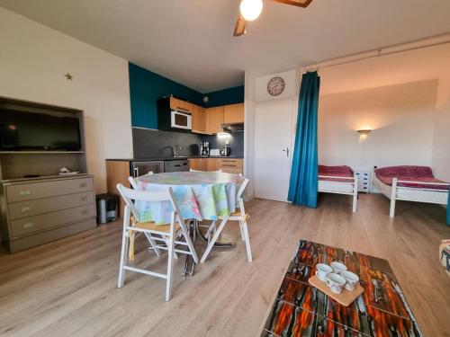 un salon avec une table et des chaises et une cuisine dans l'établissement La Cabane Maddyblue 5 min à pieds de l'Océan et commerce, à Mimizan