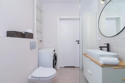 a white bathroom with a toilet and a mirror at Tauron Arena Premium Apartment with Underground & Outdoor Parking by Renters Prestige in Krakow