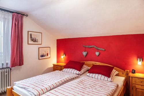 dwa łóżka w sypialni z czerwoną ścianą w obiekcie Barbara Jais w mieście Mittenwald