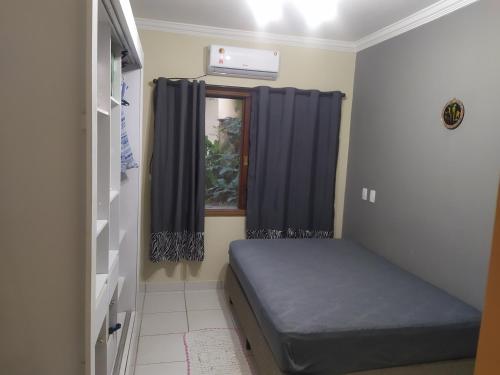 a small room with a bed and a window at Casa na praia de maresias em condomínio na avenida da praia com piscina aquecida in Maresias