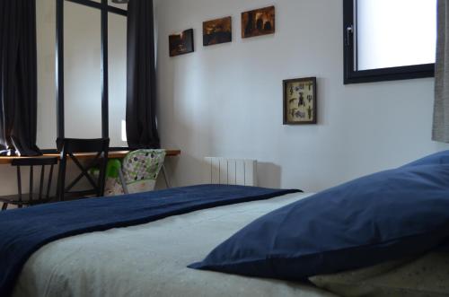 a bedroom with a bed with blue sheets and a desk at Gite Du Petit Coteau in Vouvray