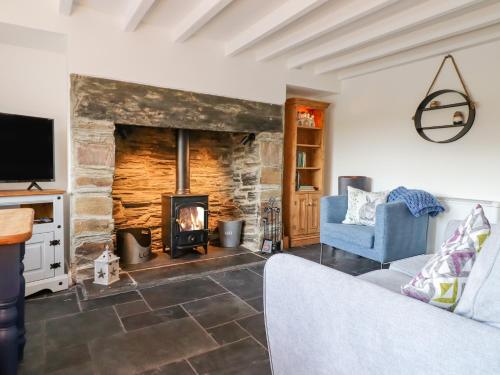 a living room with a fireplace and a blue chair at Ael Y Bryn in Blaenau-Ffestiniog