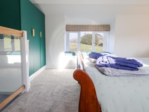 a bedroom with a bed with a chair and a window at Ael Y Bryn in Blaenau-Ffestiniog