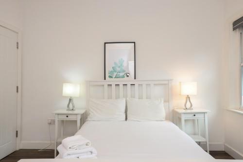 una camera bianca con un letto bianco e due lampade di Serviced Apartments In Liverpool City Centre - L1 Boutique by Happy Days a Liverpool