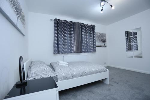 a white bedroom with a bed and a window at Abbeywood Station House London in London