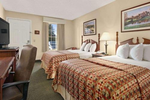 um quarto de hotel com duas camas e uma secretária e uma televisão em Baymont by Wyndham Eufaula em Eufaula