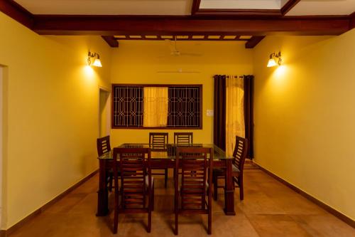 a dining room with yellow walls and a table and chairs at The Mayflower - Heritage Villa in Alleppey