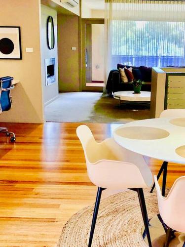 a living room with a table and white chairs at Hepburn Hideaway Villa ~ Hepburn / Daylesford in Hepburn Springs