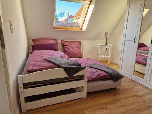 Dormitorio pequeño con cama con sábanas moradas en Heideherz en Soltau