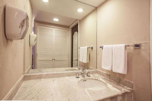 a bathroom with a sink and a mirror and towels at CHN Hotel Monterrey Norte, Trademark Collection by Wyndham in Monterrey