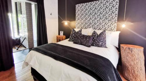 1 dormitorio con 1 cama grande con almohadas blancas y negras en House of Pinardt en Robertson