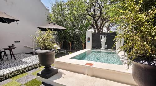 una piscina en un patio con plantas y sombrilla en House of Pinardt en Robertson