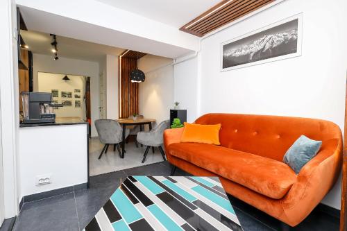 ein Wohnzimmer mit einem orangenen Sofa und einer Küche in der Unterkunft Ioana Residence Bucovina in Câmpulung Moldovenesc