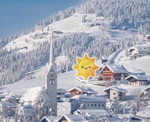 a town in the snow with a sun sign on it at dolomit24 | design apARTments in Sillian