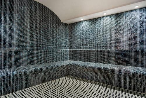a bathroom with black tiled walls and a tub at Ramada Plaza by Wyndham Ordu in Ordu