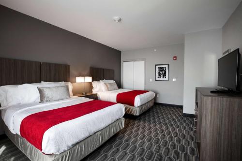 a hotel room with two beds and a flat screen tv at StoneHill Lawrence, Trademark Collection by Wyndham in Lawrence