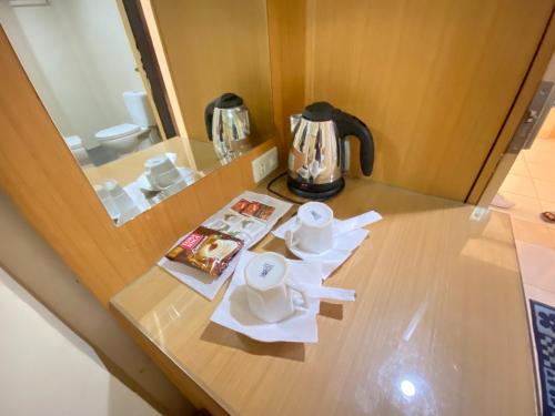 a table with affeepot and a tea kettle on it at Lilianto Hotel Polewali Mitra RedDoorz in Campalagiang
