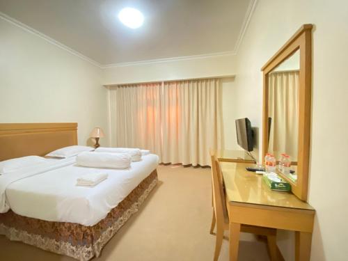 a bedroom with a bed and a desk with a mirror at Lilianto Hotel Polewali Mitra RedDoorz in Campalagiang