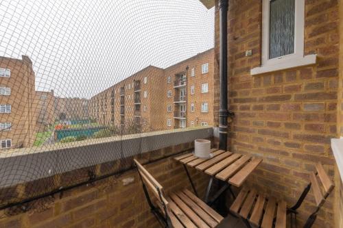 a balcony with a table and two benches on a brick wall at Stylish and Central 1 Bedroom Flat in Maida Vale in London