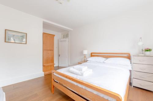 a bedroom with a bed with white sheets and a dresser at Stylish and Central 1 Bedroom Flat in Maida Vale in London