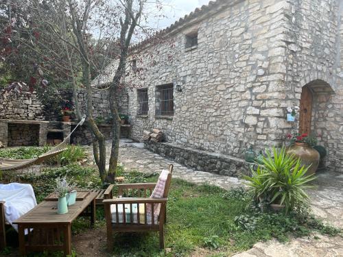a stone building with two chairs and a wooden table at Masiadenjust in Rojals