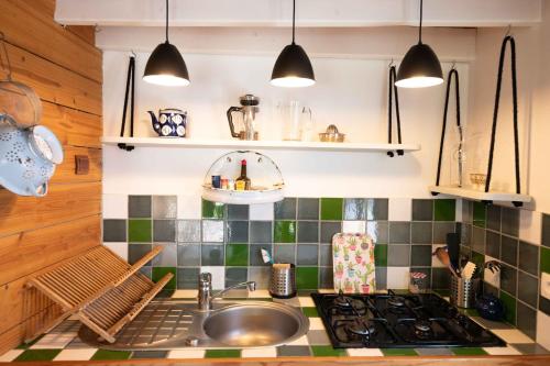 - une cuisine avec un évier, une cuisinière et des lumières dans l'établissement La Petite Maison De Papaye, au Palais