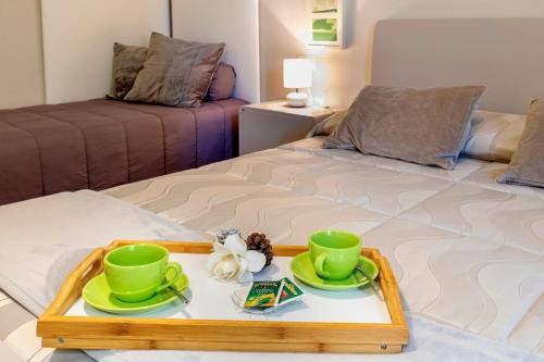 a tray with two green cups and saucers on a bed at Musica Guest House in Alghero