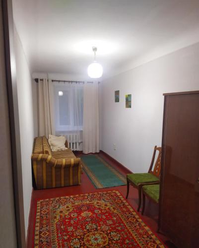 Zimmer mit einem Bett, einem Stuhl und einem Teppich in der Unterkunft 3-х комнатная квартира по улице Коцюбинского, дом 9 дробь 6 in Krementschuk