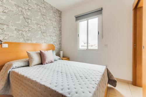 ein Schlafzimmer mit einem großen Bett und einem Fenster in der Unterkunft Home2Book El Perenquén Las Canteras in Las Palmas de Gran Canaria