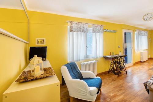 a yellow living room with a chair and a tv at Il giardino di Belgirate in Belgirate