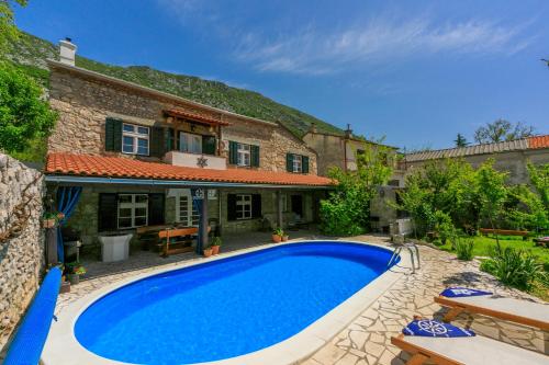a large blue swimming pool in front of a house at Santa Barbara in Drivenik