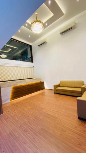 a living room with a wooden floor and a couch at Hotel Plaza Heights by RAK Rooms, Mangaluru in Mangalore
