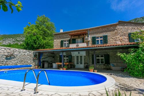 a villa with a swimming pool in front of a house at Santa Barbara in Drivenik